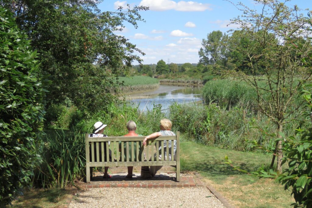 A photo depicting people relaxing on a bench overlooking the River Blackwater